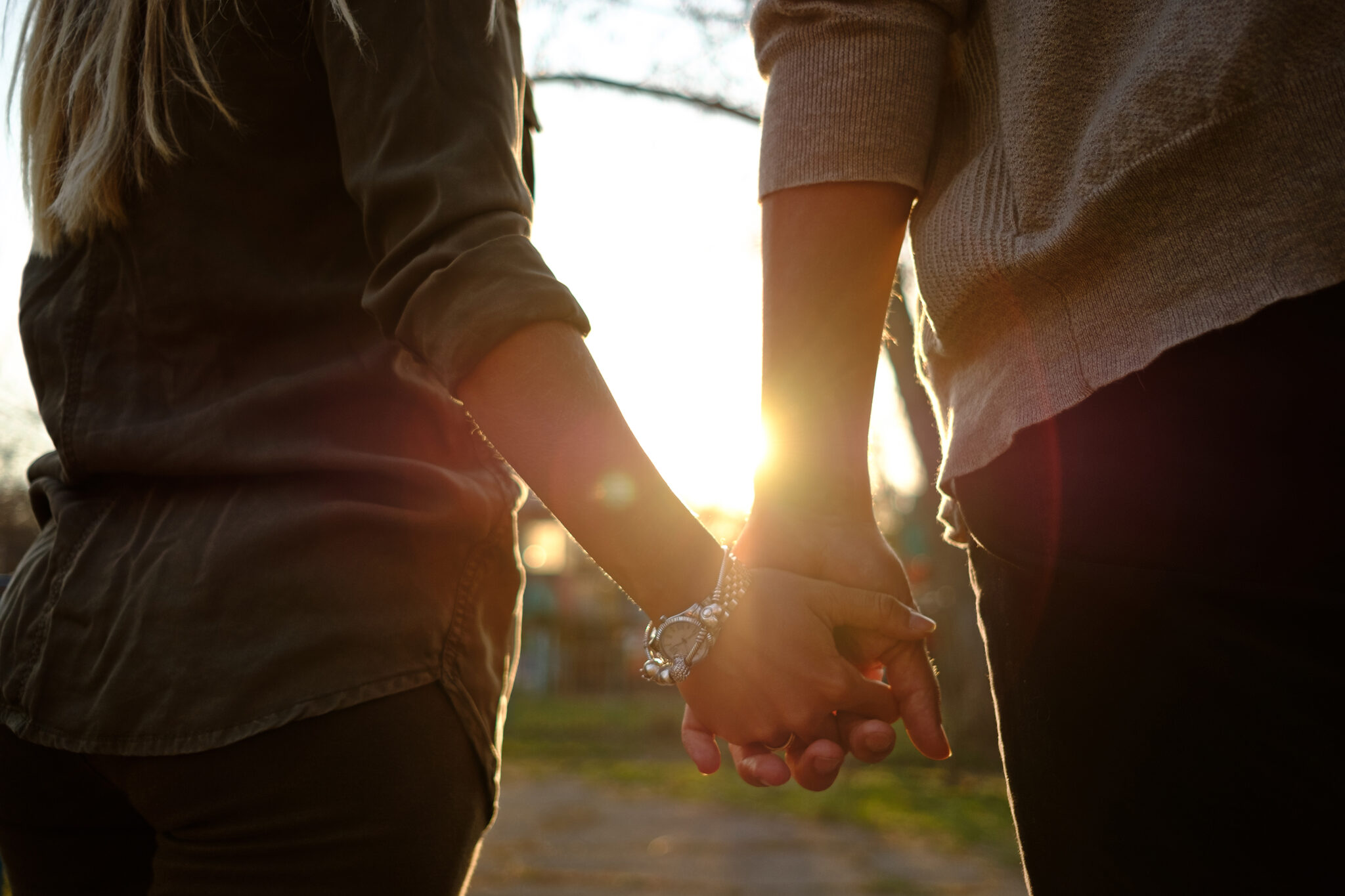 Happy smiling couple in love hug and kiss each other in the amusement park. Sunny warm spring evening